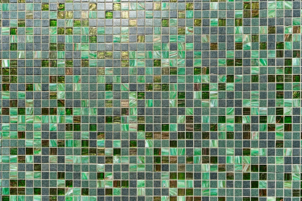 Mosaic of small square glass tiles in light and dark greens, with grey and amber tiles scattered between them