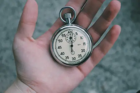A mechanical stopwatch resting in an open palm, the sweep hand at zero