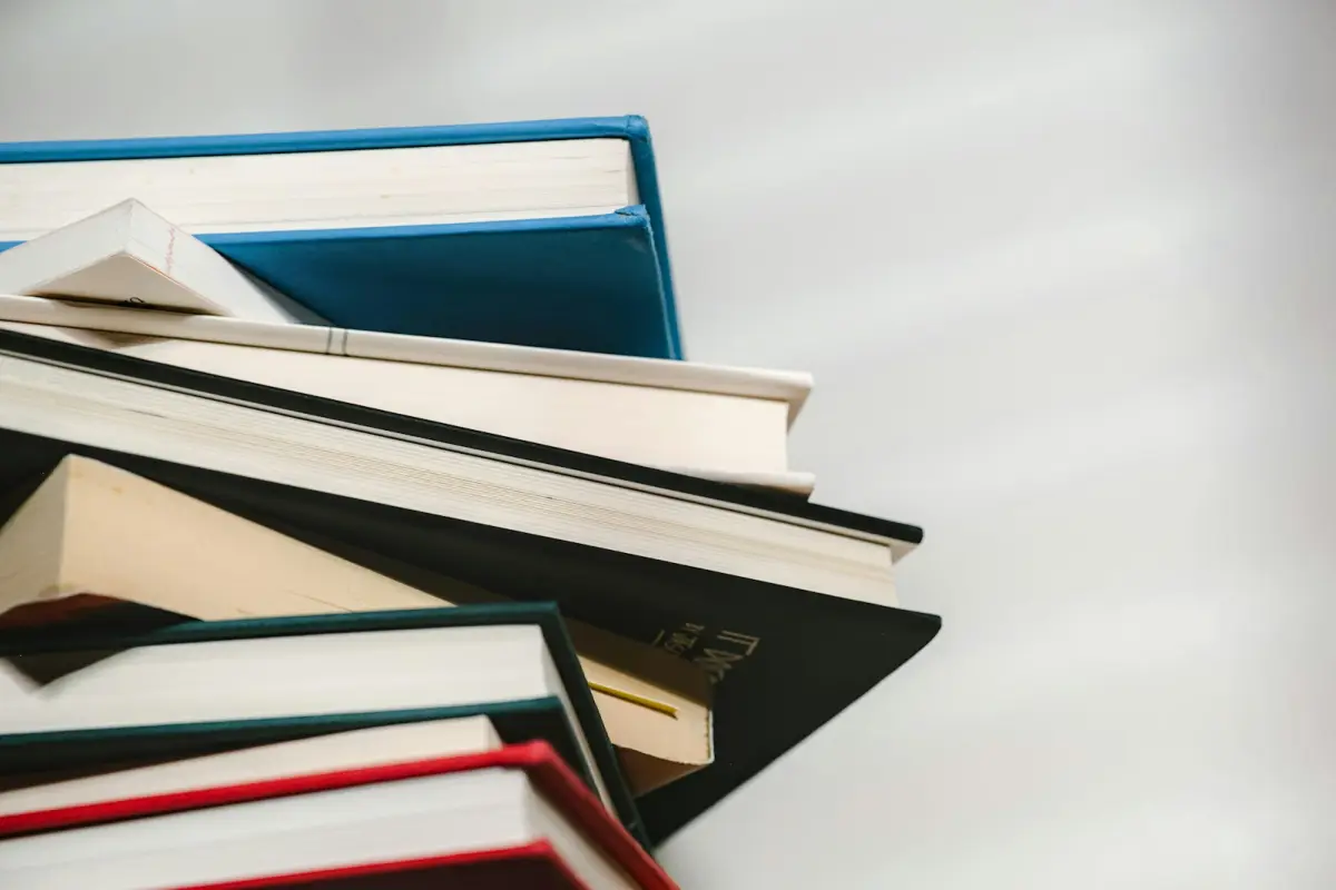A stack of hardback books of different thicknesses seen from below against a pale background, a blue cover at the top and a red one at the bottom