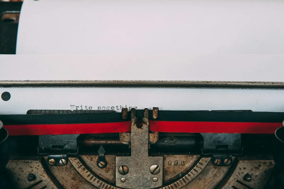 Nahaufnahme einer alten Schreibmaschine mit eingespanntem Blatt, darauf die getippte Zeile „Write something