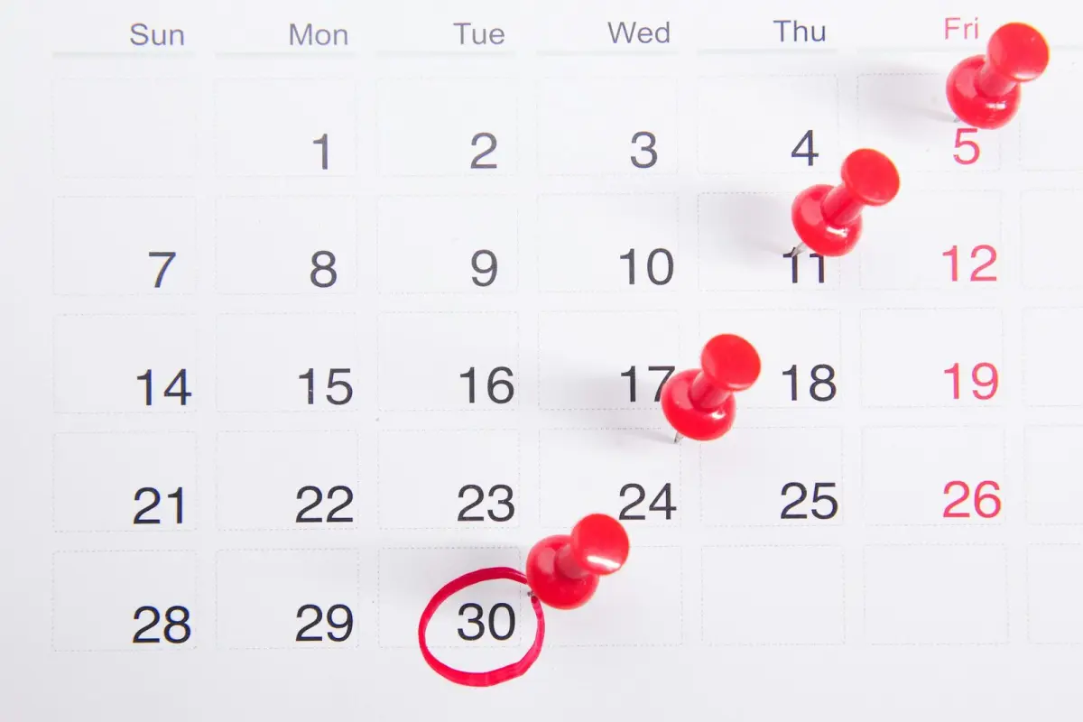 A monthly calendar with single days marked by red push pins, the 30th circled in red