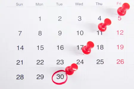 A monthly calendar with single days marked by red push pins, the 30th circled in red