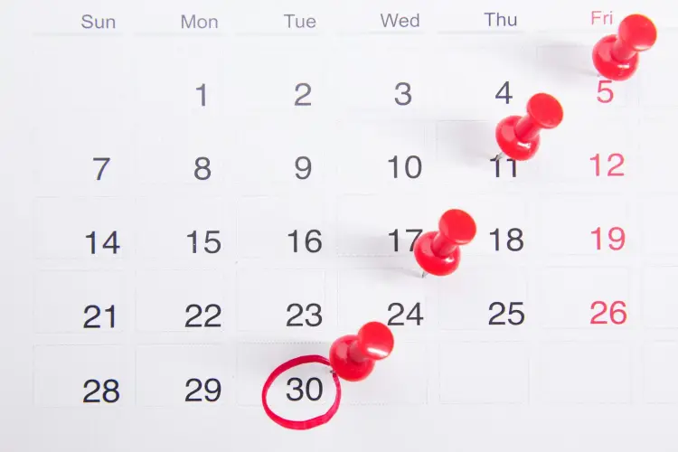 A monthly calendar with single days marked by red push pins, the 30th circled in red